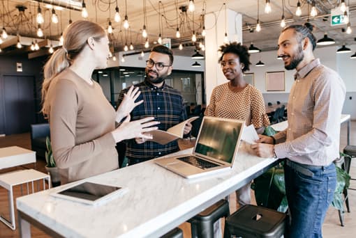 technology marketing coworkers standing around laptop